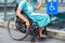 Young disabled woman in wheelchair near handicapped walkway sign, transportation convenience for disabled people concept