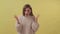 Young disappointed girl standing isolated over yellow background while looking camera