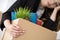 Young dismissed female worker in office holding carton box with