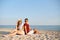 Young diverse race couple sitting back to back on beach towel at tropical travel location. Lovers at beautiful sea view