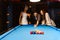 Young diversity group of people playing pool together with smile, enjoyment and fun. Young people spend time in billiards room.