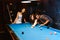 Young diversity group of people playing pool together with smile, enjoyment and fun. Young people spend time in billiards room.