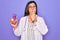 Young doctor cardiology specialist woman holding medical heart over pruple background cover mouth with hand shocked with shame for