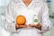 Young doctor holding grapefruit and bottle of pills with vitamin