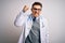 Young doctor man with blue eyes wearing medical coat and stethoscope over isolated background angry and mad raising fist