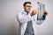 Young doctor man wearing medical coat looking at chest scan radiography over isolated background with a happy face standing and