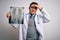 Young doctor man wearing medical coat looking at chest scan radiography over isolated background stressed with hand on head,