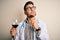Young doctor man wearing stethoscope drinking a glass of fresh wine over isolated background serious face thinking about question,
