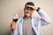 Young doctor man wearing stethoscope drinking a glass of fresh wine over isolated background stressed with hand on head, shocked