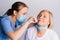 A young doctor in a medical mask takes a COVID 19 test, nasal swab from an elderly woman against a white background