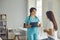 Young doctor talking to female patient in office of modern clinic, giving her useful medical advice