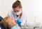 Young doctor in white is taking examination of a child on the chair