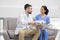 Young doctor in whitecoat talking to his pretty assistant in blue uniform