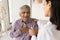 Young doctor woman calming senior Indian patient, holding mans hand