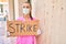 Young doctor woman wearing medical mask and holding strike banner cardboard at street of city