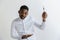 Young doubting attractive african american guy holding empty dish and fork isolated on grey background.