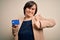 Young down syndrome business woman holding credit card as customer payment happy with big smile doing ok sign, thumb up with