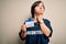 Young down syndrome volunteer woman wearing social care charity t-shirt showing identification serious face thinking about