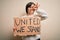 Young down syndrome woman holding protest banner with united we stand rights message with happy face smiling doing ok sign with