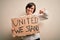 Young down syndrome woman holding protest banner with united we stand rights message very happy pointing with hand and finger