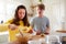 Young Downs Syndrome Couple Decorating Homemade Cupcakes With Icing In Kitchen At Home