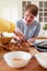 Young Downs Syndrome Couple Decorating Homemade Cupcakes With Icing In Kitchen At Home