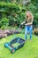 Young dutch woman pushing lawn mower on grass