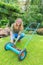 Young dutch woman reparing lawn mower in garden