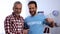 Young and elderly men showing volunteer word on t-shirt to camera, charity