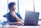 Young elegant banking finance analyst working at sunny office on laptop while sitting at wooden table.Businessman