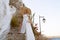 young elegant woman wearing straw hat and white dress standing on stars at old town - Greece, Spetses