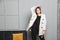 Young elegant woman in white oversize blazer and black ripped pants. Interior portrait