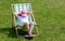 Young elementary school age child, girl laying on a sunbed, relaxing, sleeping, taking a nap outdoors in the garden alone. Leisure