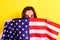 Young embarrassed woman covers herself with an American flag to maintain privacy and protect herself from abuse