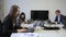 Young employees working at desk with laptops sitting in company.