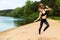 Young energetic girl who is engaged in fitness on the beach near the river