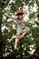 Young energetic woman in long gray shirt jumps high in the air