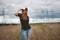 Young energy happy woman wears a cap hip-hop on yellow field with power pylons, wide angle