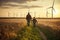 Young engineer caring for his daughter and looking at windmill field at sunset, concept of renewable energy, love, nature, family