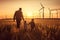 Young engineer caring for his daughter and looking at windmill field at sunset, concept of renewable energy, love, nature, family