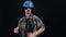 The young engineer, happy, charismatic, dances with his blue helmet. Isolated on black background. The concept of life
