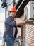 Young engineer installing air conditioner on building outer wall