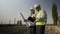 Young engineer technician and architect with helmet checking topographical map on tablet pc for future construction -