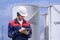 Young engineer using digital tablet to working his job in front of industrial oil tanks in refinery base