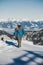 Young enthusiastic snowboarder walking at the top of a mountain with snowboard in his hand