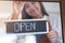 A young entrepreneur or a waitress hanging open sign on the shop front door