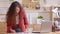 Young entrepreneur working standing at desk at home office arranging papers, managing project tasks. Professional business woman