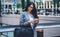 Young ethnic woman in glasses messaging on phone on street