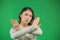 Young european asian woman gesturing stop, arms crossed, isolated on green background