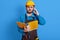 Young European bearded man working as architect or foreman, solving problems on building, holds paper folder, talking phone,